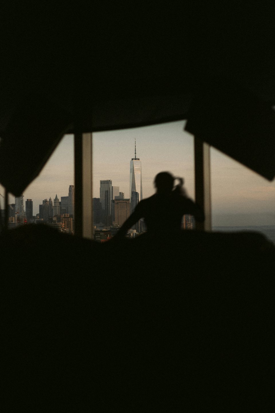 Person silhouetted against a window overlooking a city skyline.